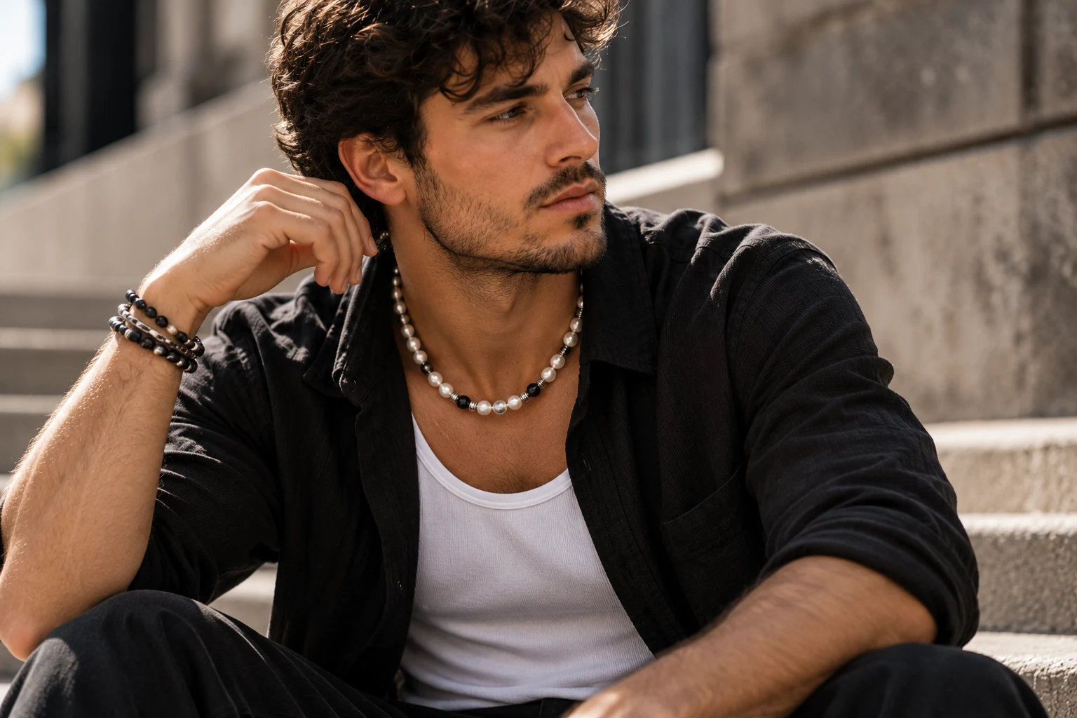 Homme au style streetwear moderne portant un collier en perles blanches et noires avec une chemise sombre, illustrant le retour des perles dans la mode masculine.